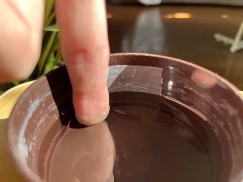 ウンベラータの容器にメンディングテープで目印を浸けた様子（指との比較）